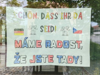 Ein Schild, auf dem jeweils auf deutsch und auf tschechisch "Schön, dass du da bist" steht.
